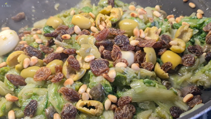 La farcitura della pizza di scarola: scarola, insaporita con aglio, olio, acciughe e capperi, con uvetta pinoli e olive verdi.