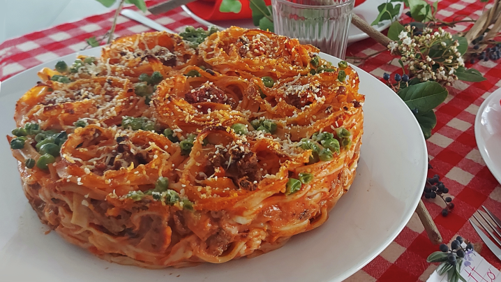 Tagliolini conditi con sugo di macinato, besciamella, provola, piselli e formaggio grattugiato, in superfifcie un delizioso decoro a rose fatto con i tagliolini.