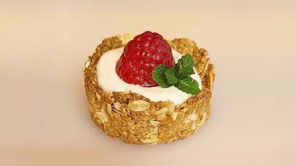 Un guscio croccante di fiocchi di avena e miele con un fresco ripieno di yogurt greco e lamponi.