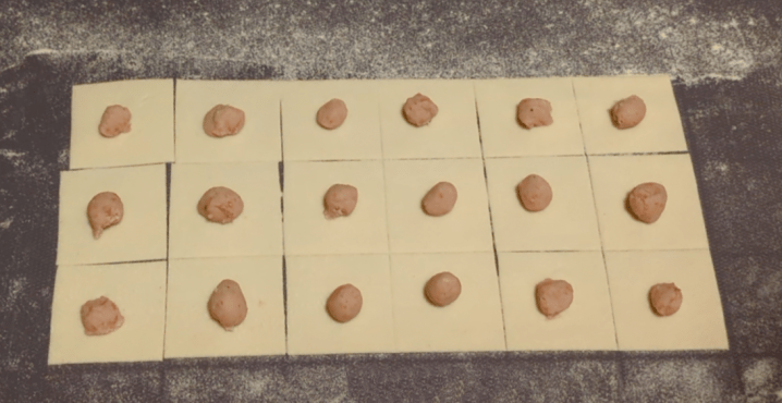 Come fare i tortellini: primo passo mettere il ripieno al centro di quadratini di sfoglia.