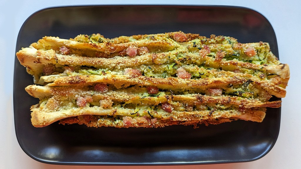 Piadine piegate a fisarmonica, con un ripieno di zucchine e pancetta, irrorate con latte e uova e gratinate al forno.